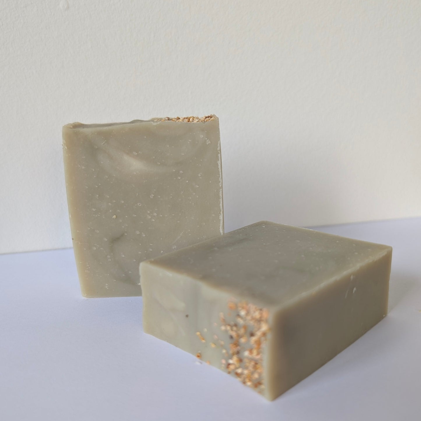 Two rectangular bars of soap on a white surface with a light gray background